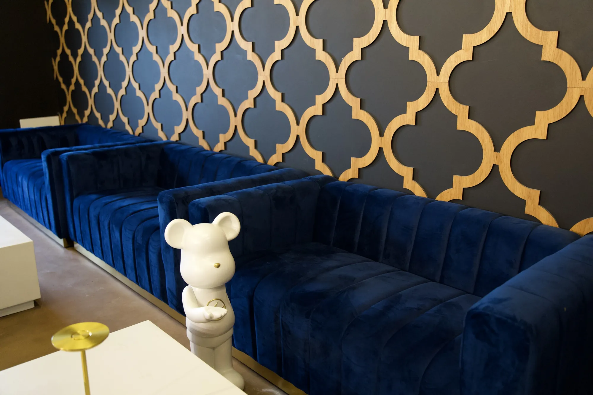 Deep navy velvet booths against a gold patterned wall